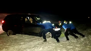 Maşină deszăpezită cu lopata de jandarmii din Vâlcea, după ce o familie de turişti a rămas blocată. FOTO