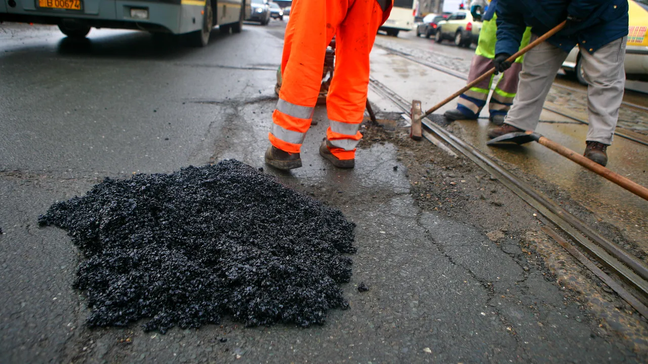 Drumarii dintr-un municipiu asfaltează iarna gropile folosind butelii cu arzător
