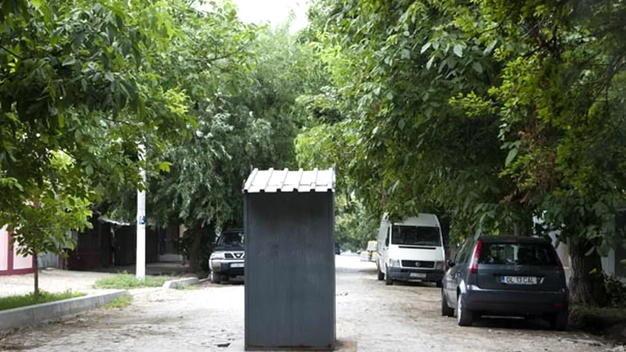 Toaleta din mijlocul străzii: Muncitorii care repară drumul au aşezat pe o gură de canalizare fără capac o cabină din tablă