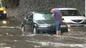 Apă de 15 cm, acumulată pe un drum naţional, după o ploaie torenţială. Circulaţia rutieră se desfăşoară cu dificultate 