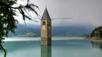 Satul italian unde clopotele bat sub apă. Turnul iese la suprafață dintr-un lac alpin