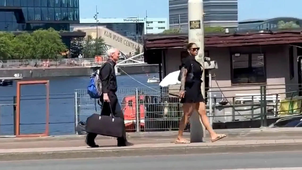 Femeie filmată în timp ce se plimbă și ține în lesă un bărbat cu părul cărunt