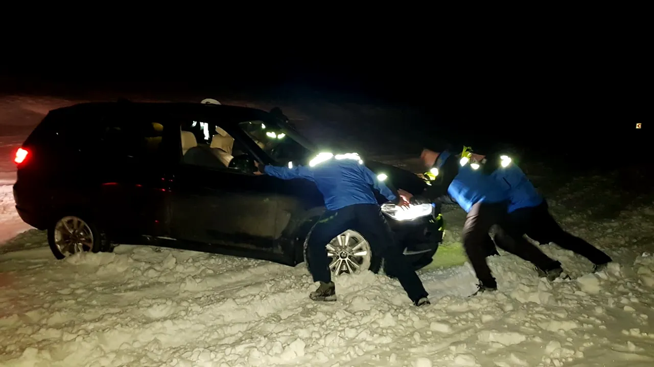 Maşină deszăpezită cu lopata de jandarmii din Vâlcea, după ce o familie de turişti a rămas blocată. FOTO