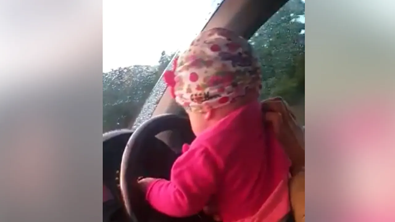 Un bărbat a fost filmat în timp ce conduce cu fetiţa lui în braţe | VIDEO