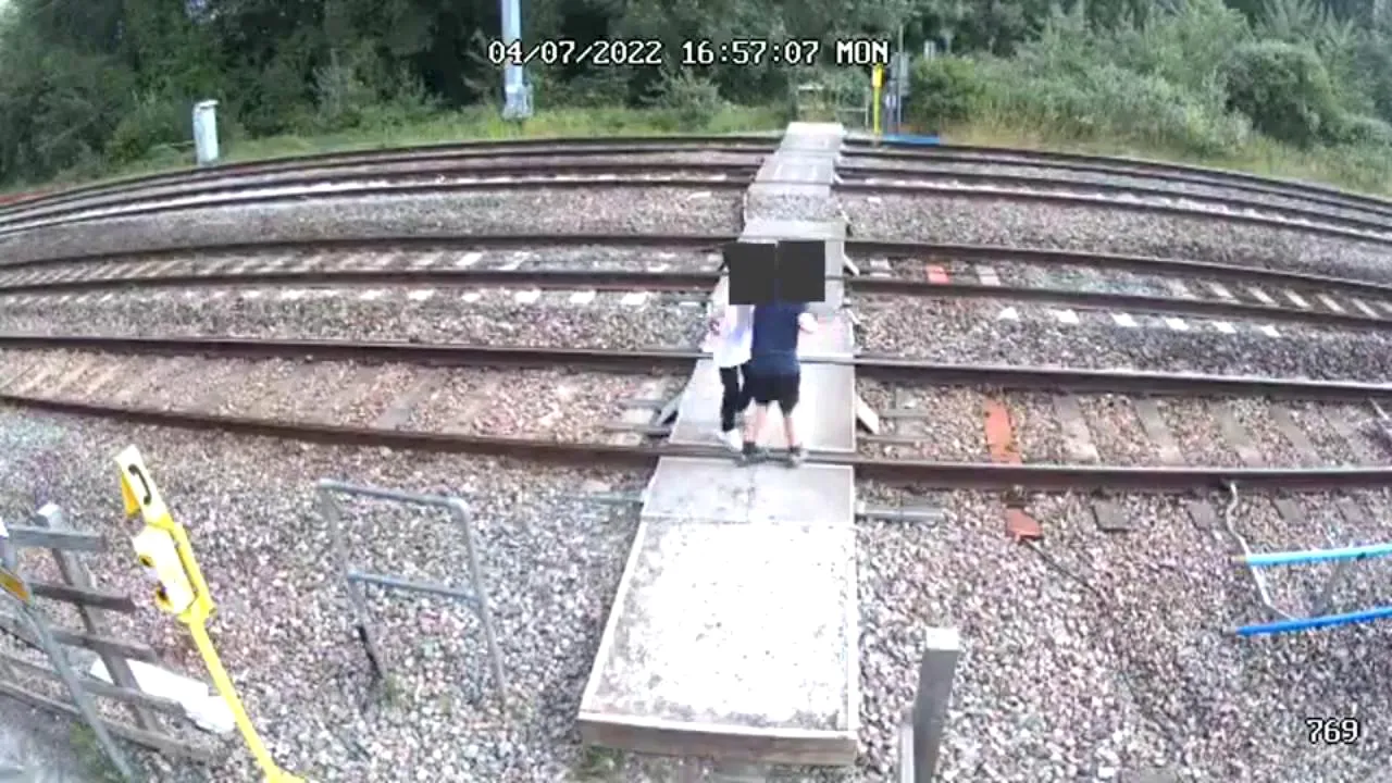 Doi copii dansează pe şine, în timp ce un tren trece cu viteză de 200 km/h, iar doi adulţi urmăresc scena