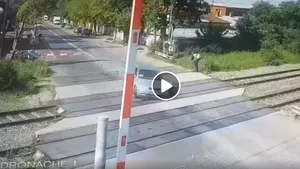 Filmare la o trecere la nivel cu calea ferată din Bucureşti. O maşină accelerează şi trece, la limită, printre bariere