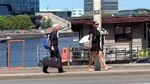 Femeie filmată în timp ce se plimbă și ține în lesă un bărbat cu părul alb