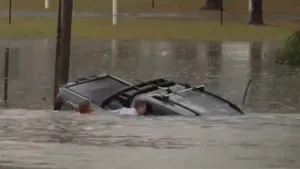 Un reporter TV a sărit în apele unei inundații pentru a salva un șofer blocat într-o mașină care se scufunda. Momentul dramatic a fost filmat