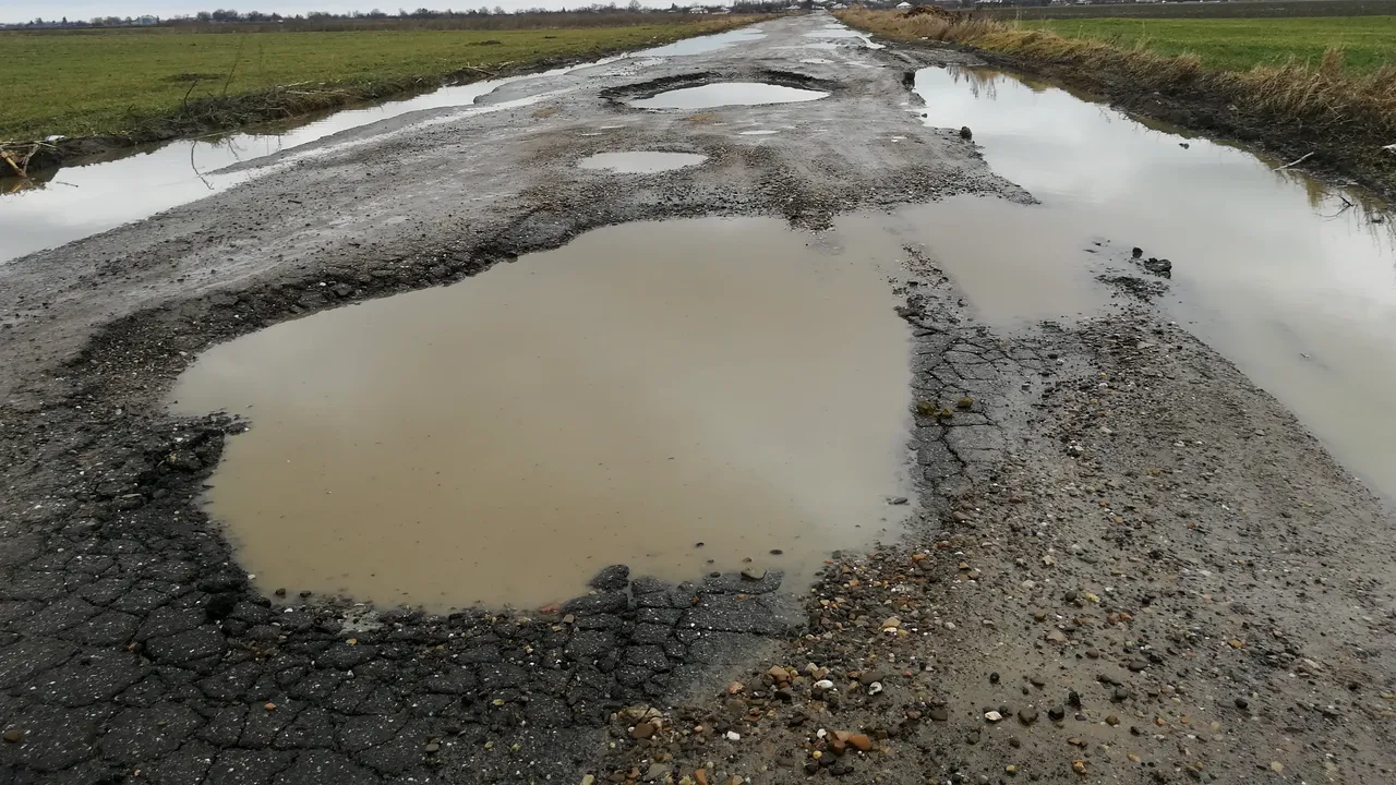 Un drum judeţean din Vrancea „dispare” când plouă. Apa se revarsă din gropi şi acoperă asfaltul