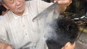 Un frizer din China practică o metodă străveche de tuns, cu cleşti încinşi în foc